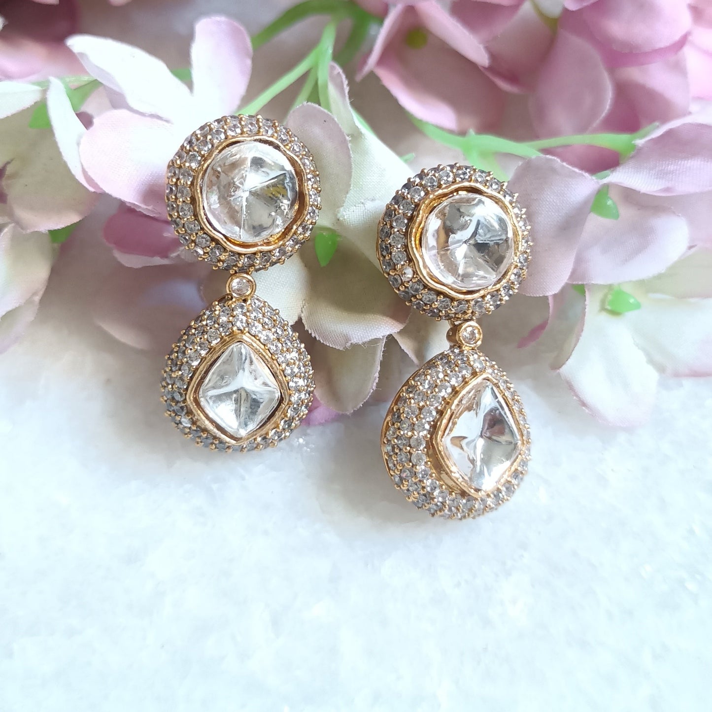 Gold toned dangler earring featuring a radiant white stone