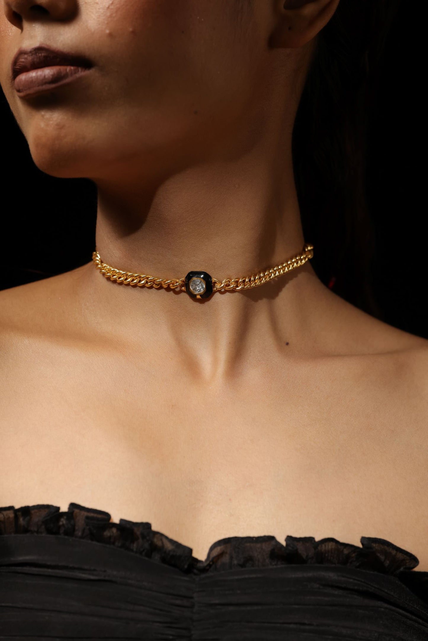 Gold toned metal pendant with a black background clear faceted stone