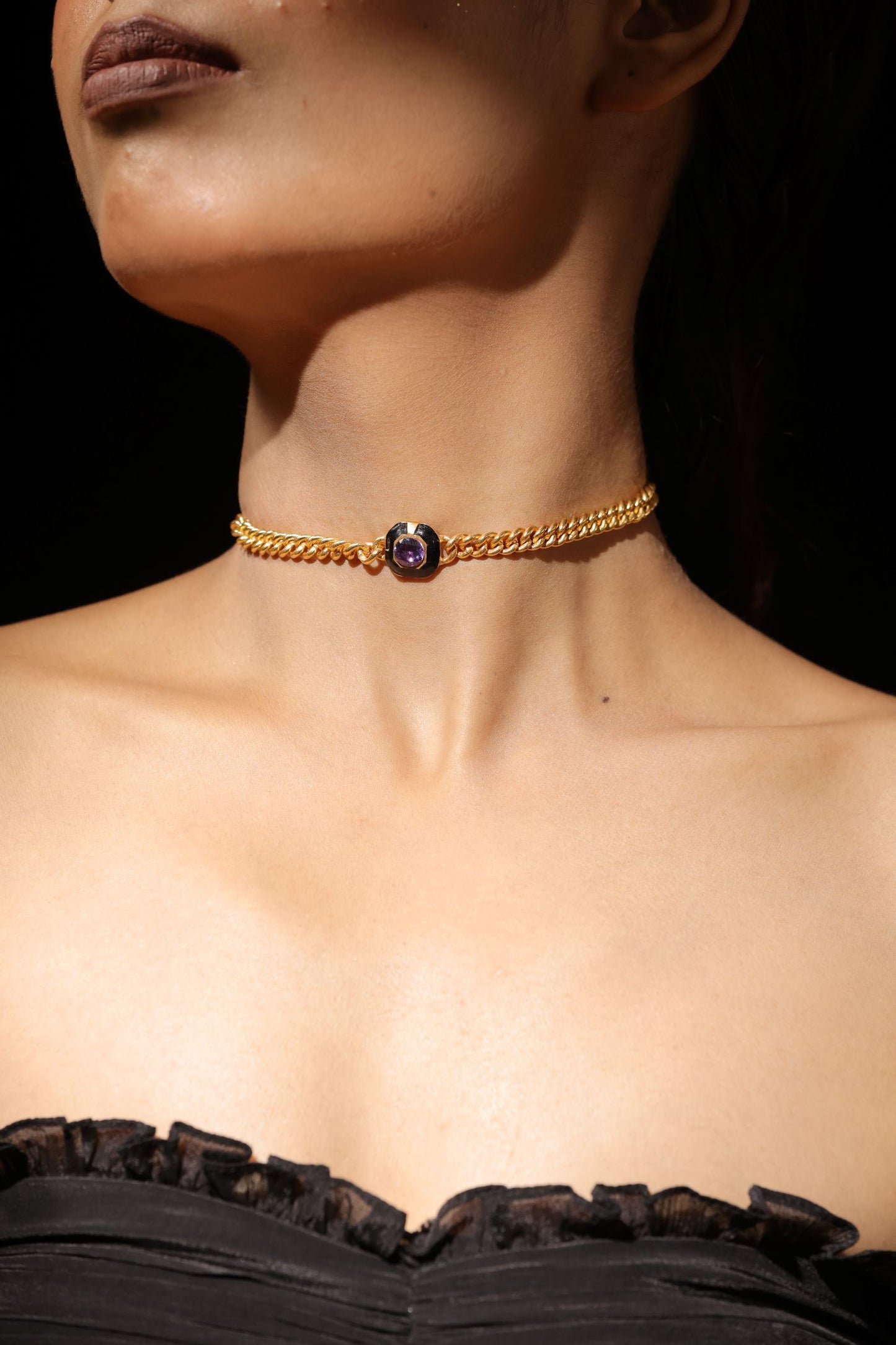 Gold toned metal pendant with a black background clear faceted stone