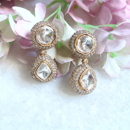 Gold toned dangler earring featuring a radiant white stone