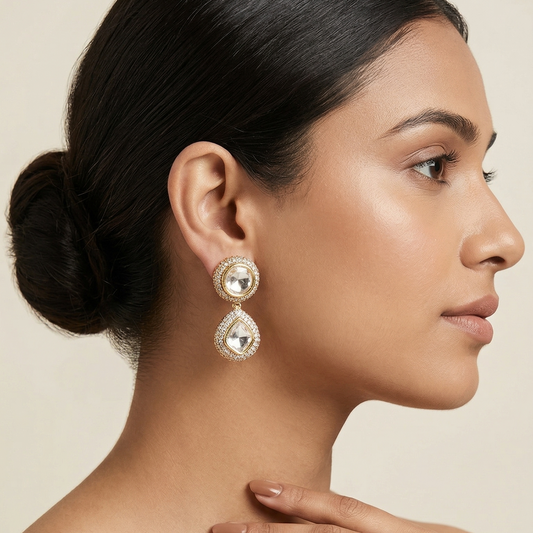 Gold toned dangler earring featuring a radiant white stone